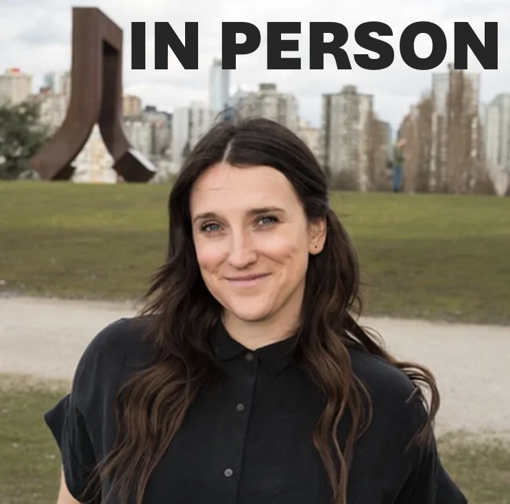 Kaela Blahey wearing a black button up shirt outside in front of green grass with a path halfway through. There are buildings in the background and greyish blue skies. There is also the words "in person" in the sky because this is an in person workshop.