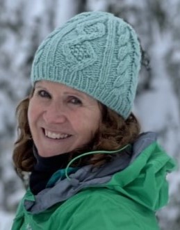 Helen Ritchie in a green jacket and touque in front of snow